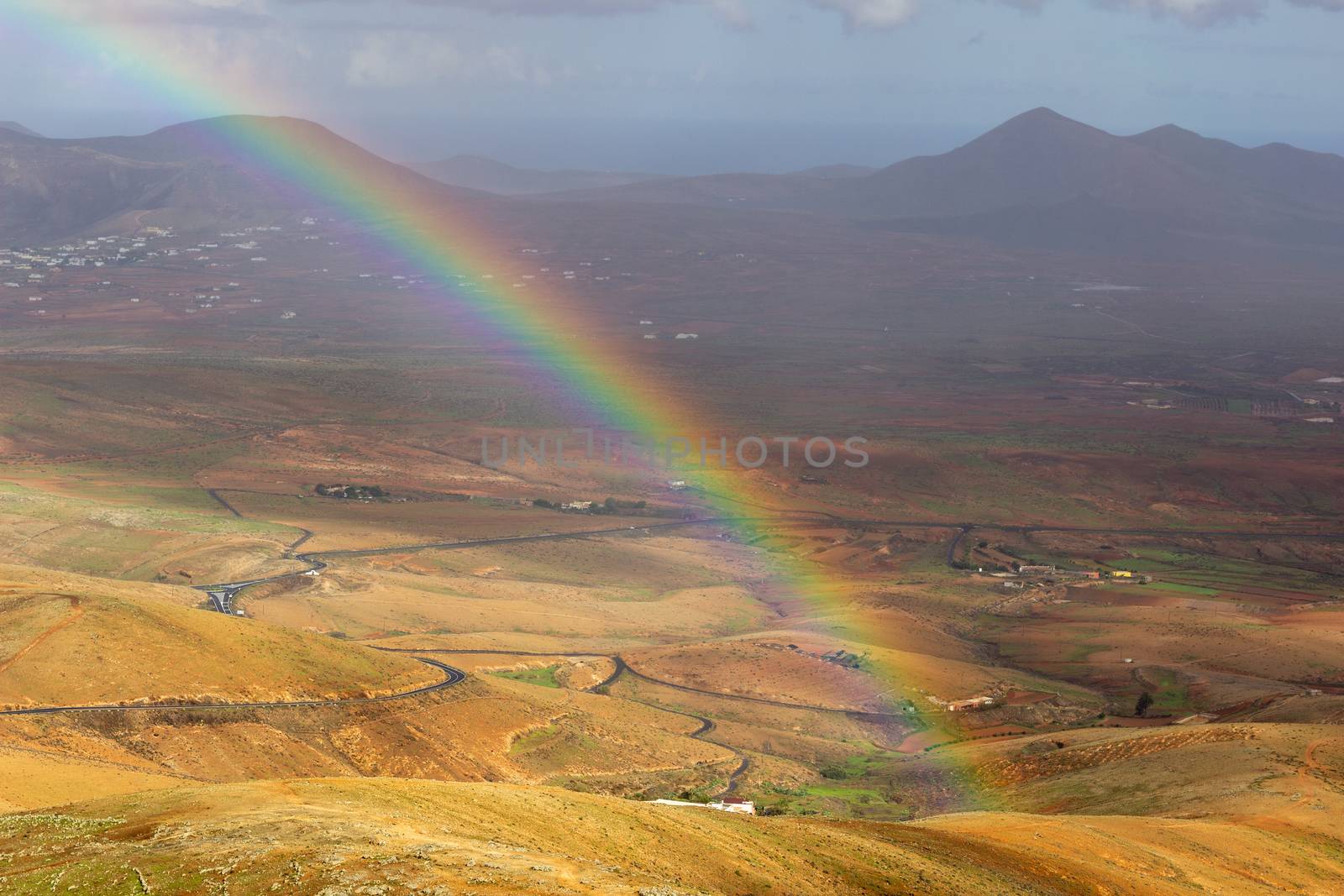 Panoramic view at landscape from viewpoint Mirador Morro Velosa on Fuerteventura, Spain with rainbow and multi colored volcanic hills