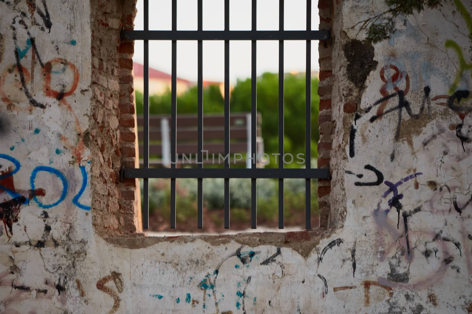 Window with rusty bars and painted graffiti of an abandoned building in a park or forest