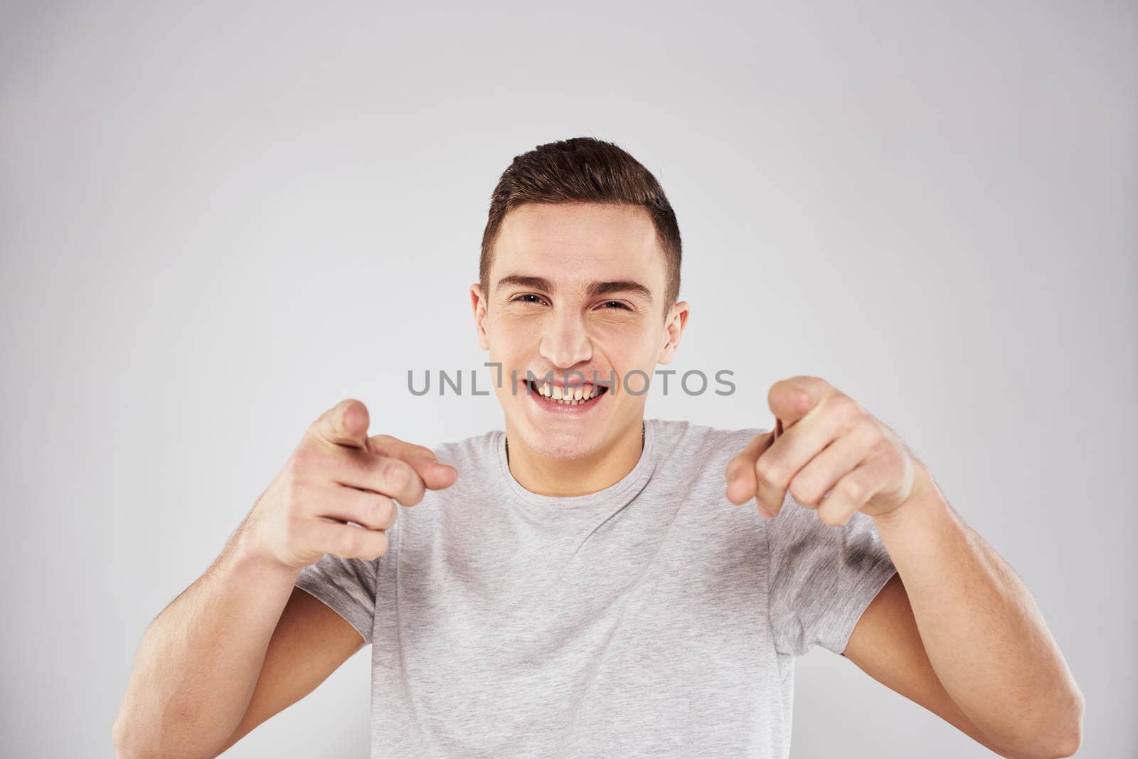 Man in a white t-shirt emotions gestures with hands close-up cropped view light background. High quality photo