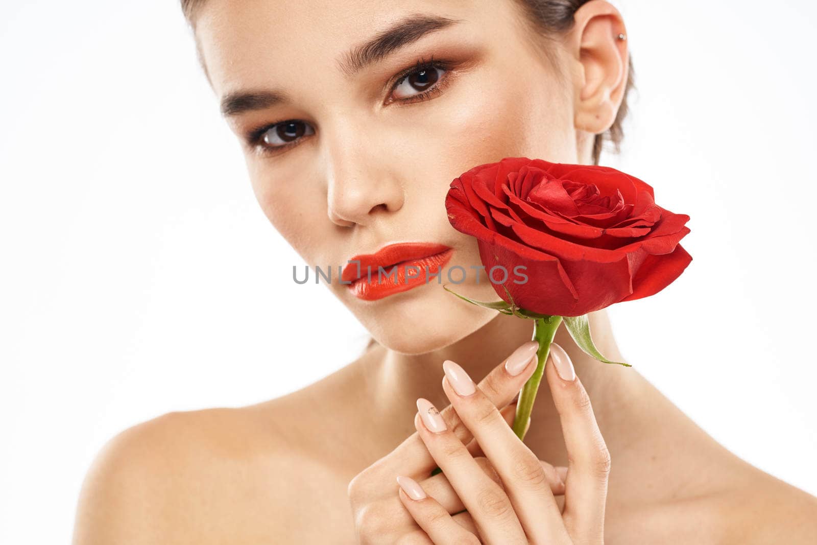 charming brunette girl with makeup on her face and a red rose in her hand. High quality photo