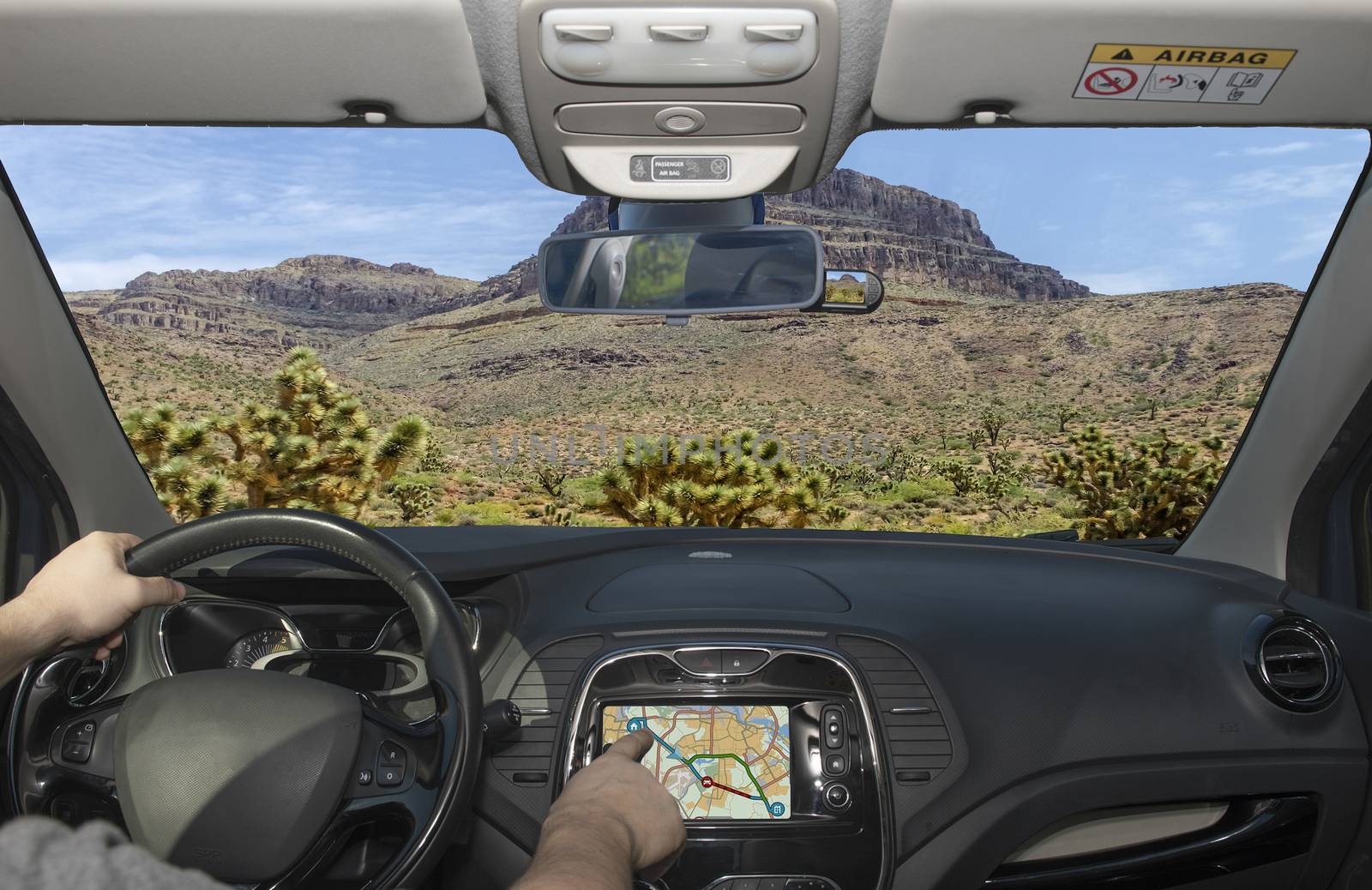 Driving a car while using the touch screen of a GPS navigation system towards Spirit Mountain among joshua trees, Grand Canyon, Arizona, USA
