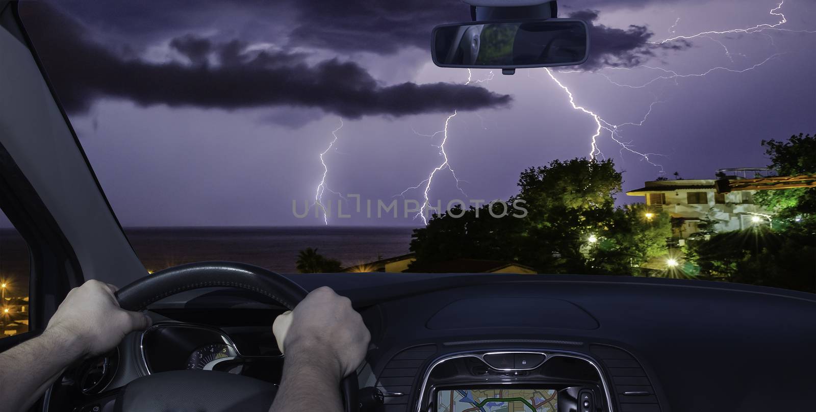 Driving a car towards a spectacular lightning storm over the sea