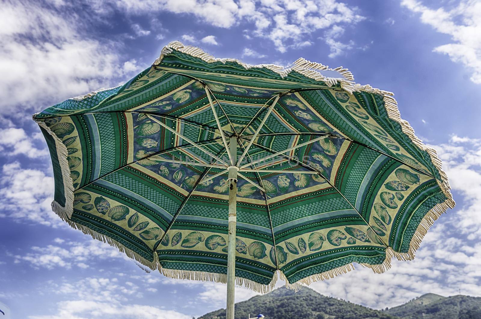Decorated green beach umbrella as seen from the ground against the background of a light sky