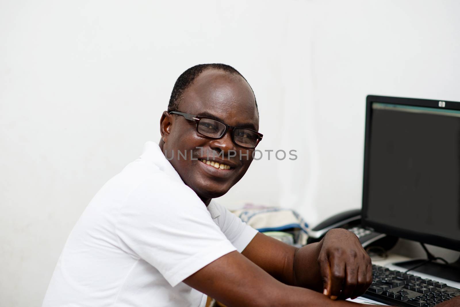 Portrait of handsome businessman man sitting at his desk with desktop computer. man at his workplace looking at the camera.