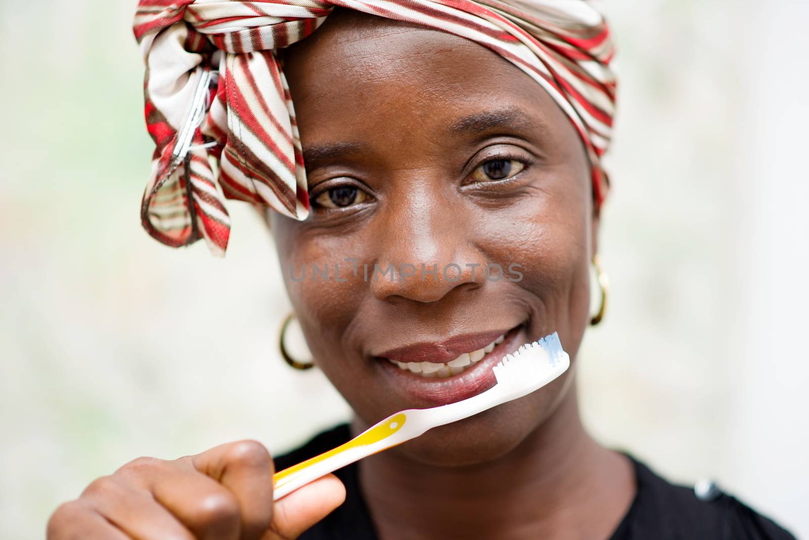 young smiling woman wearing a scarf on the head brushes the tooth