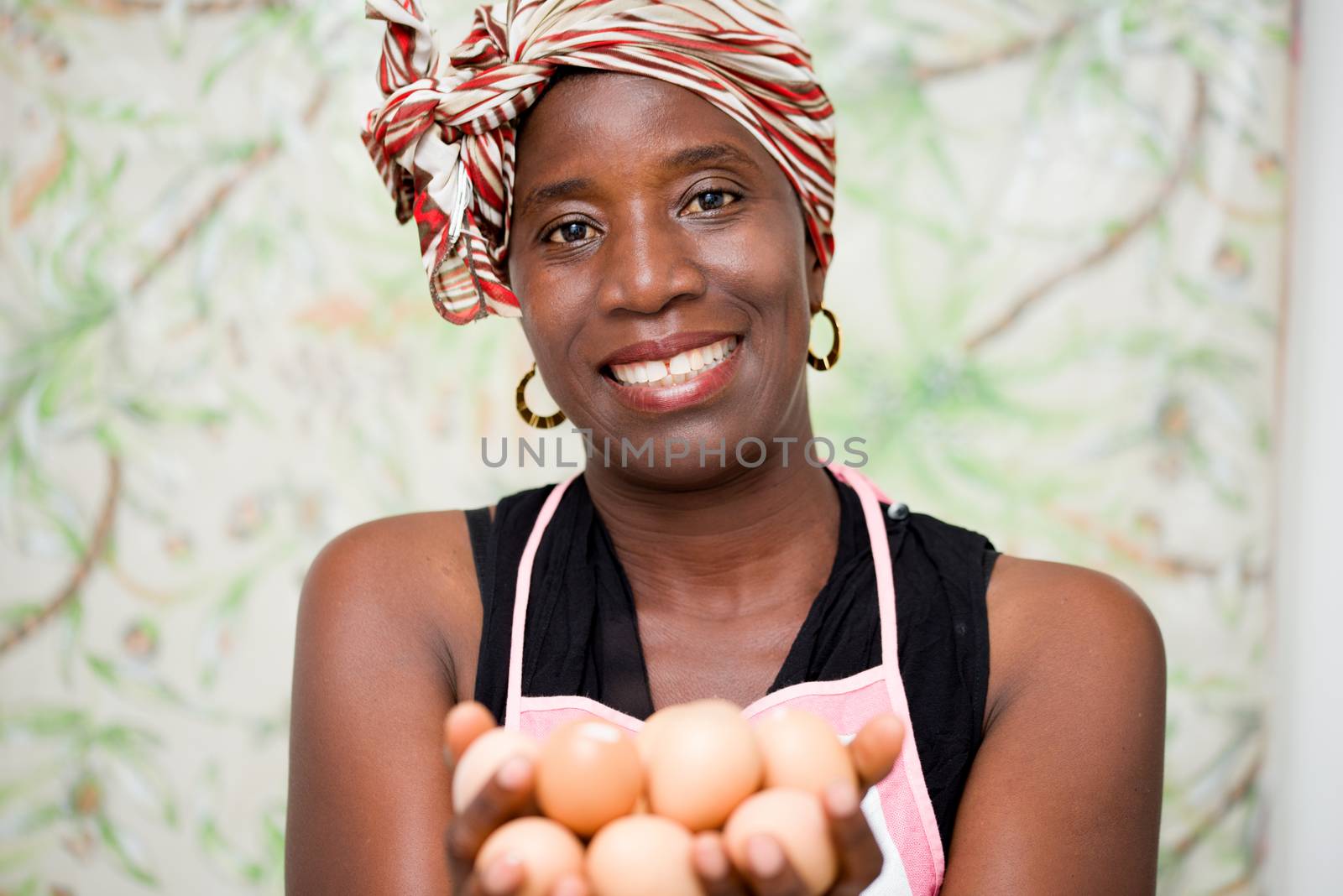 young smiling woman standing in studio and wearing apron holding eggs in hand