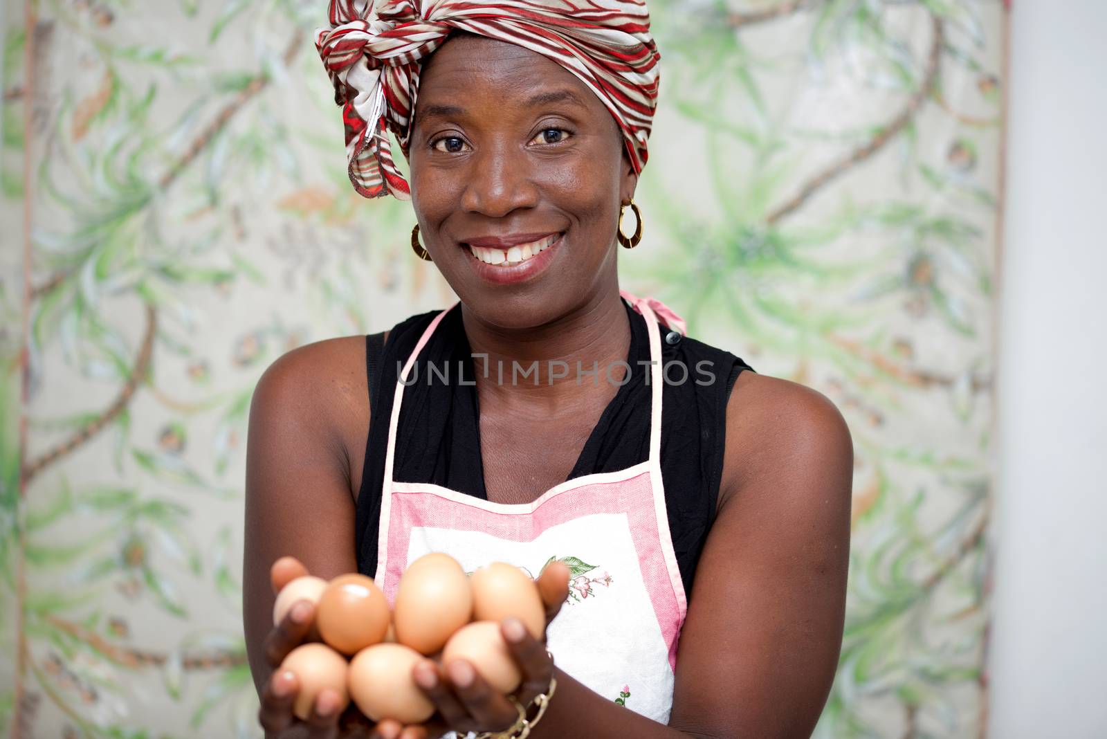 young smiling woman standing in studio and wearing apron holding eggs in hand