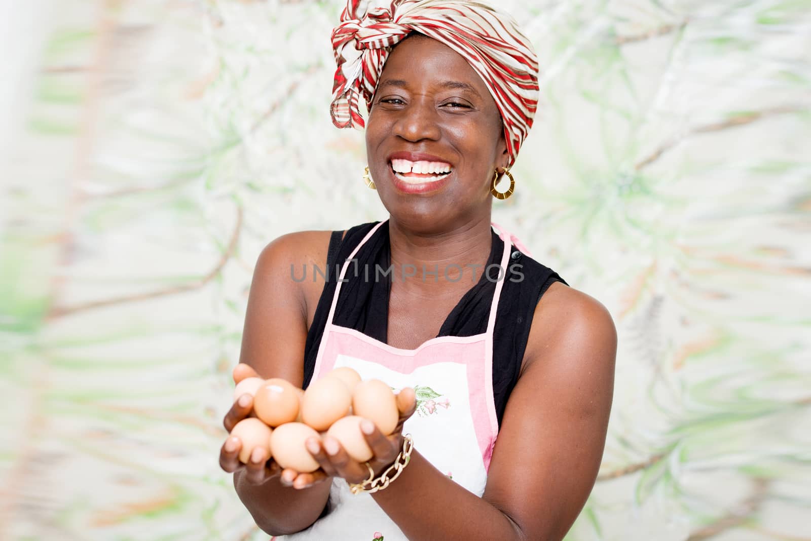 young happy woman standing in a studio with green background, holding organic eggs in hands