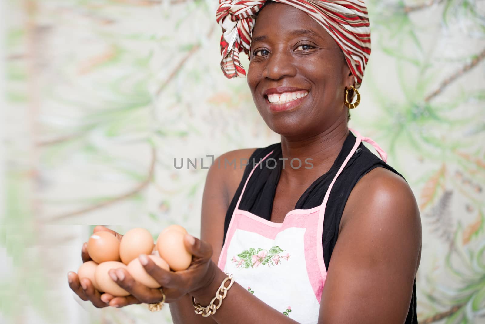 young happy woman standing in a studio with green background, holding organic eggs in hands