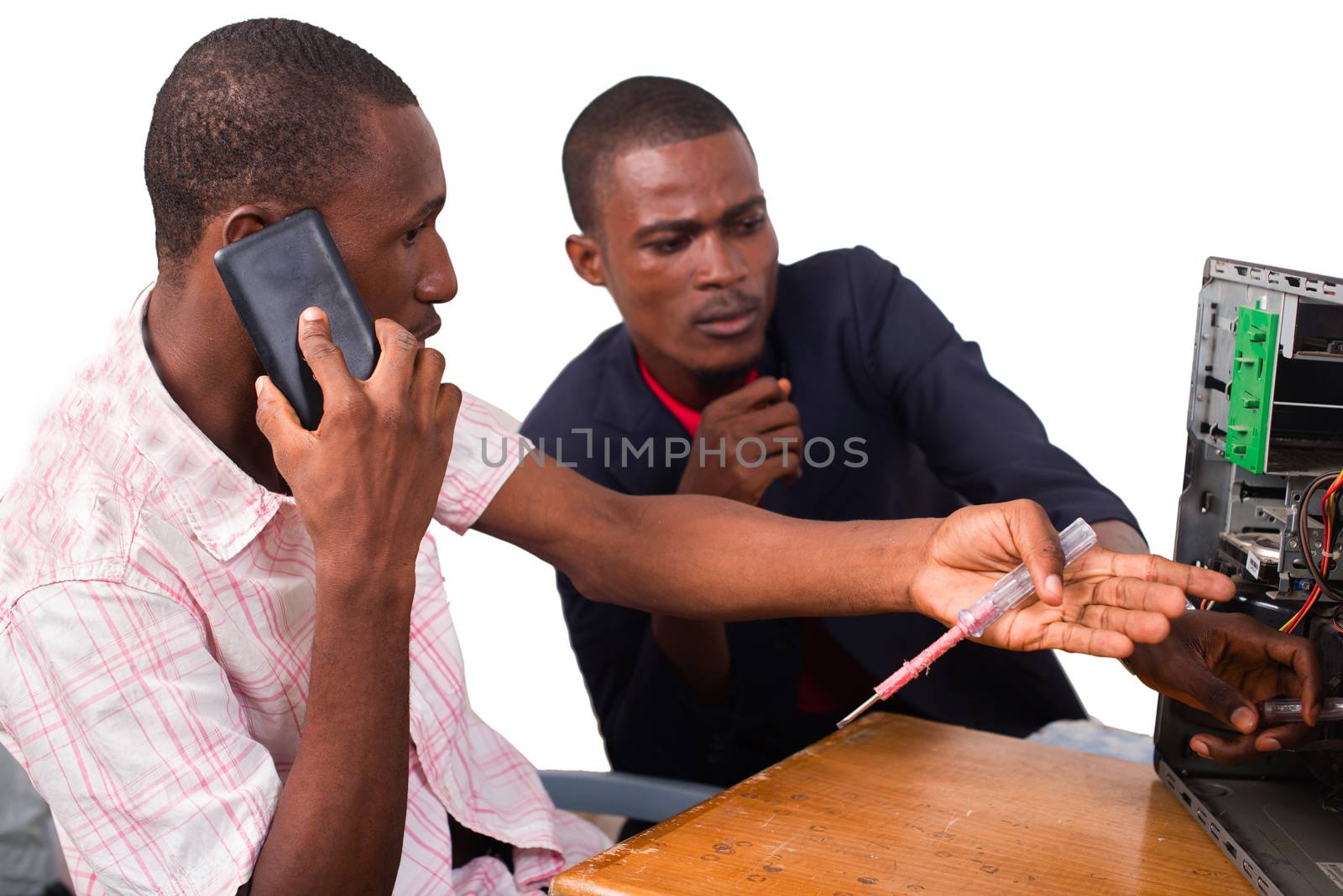 young computer technician talking on the phone and repairing a computer in front of an instructor