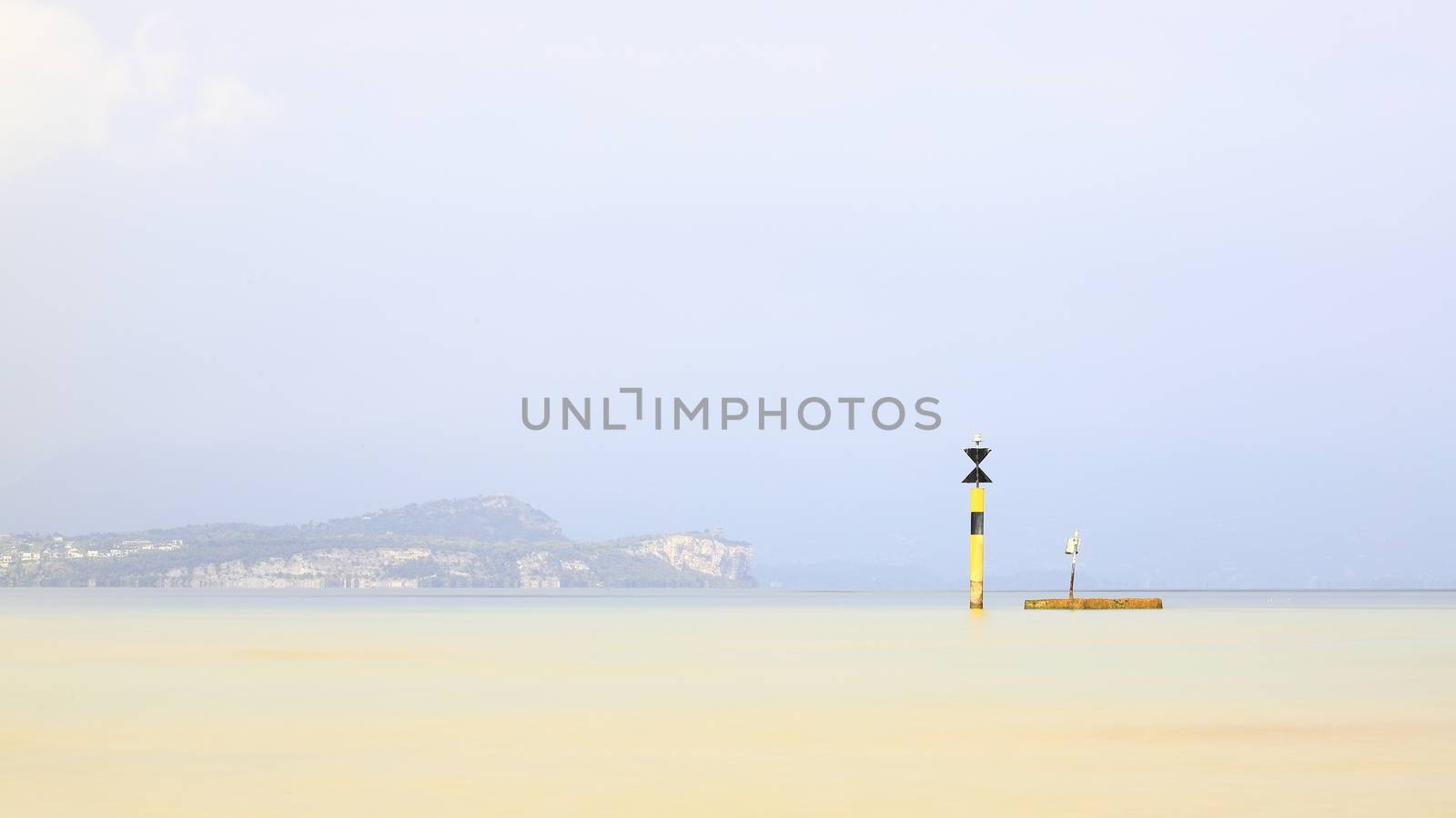 The view past a marker post across Lake Garda from the resort town of Sirmione.  Sirmione is at the southern end of the lake which is in North East Italy.