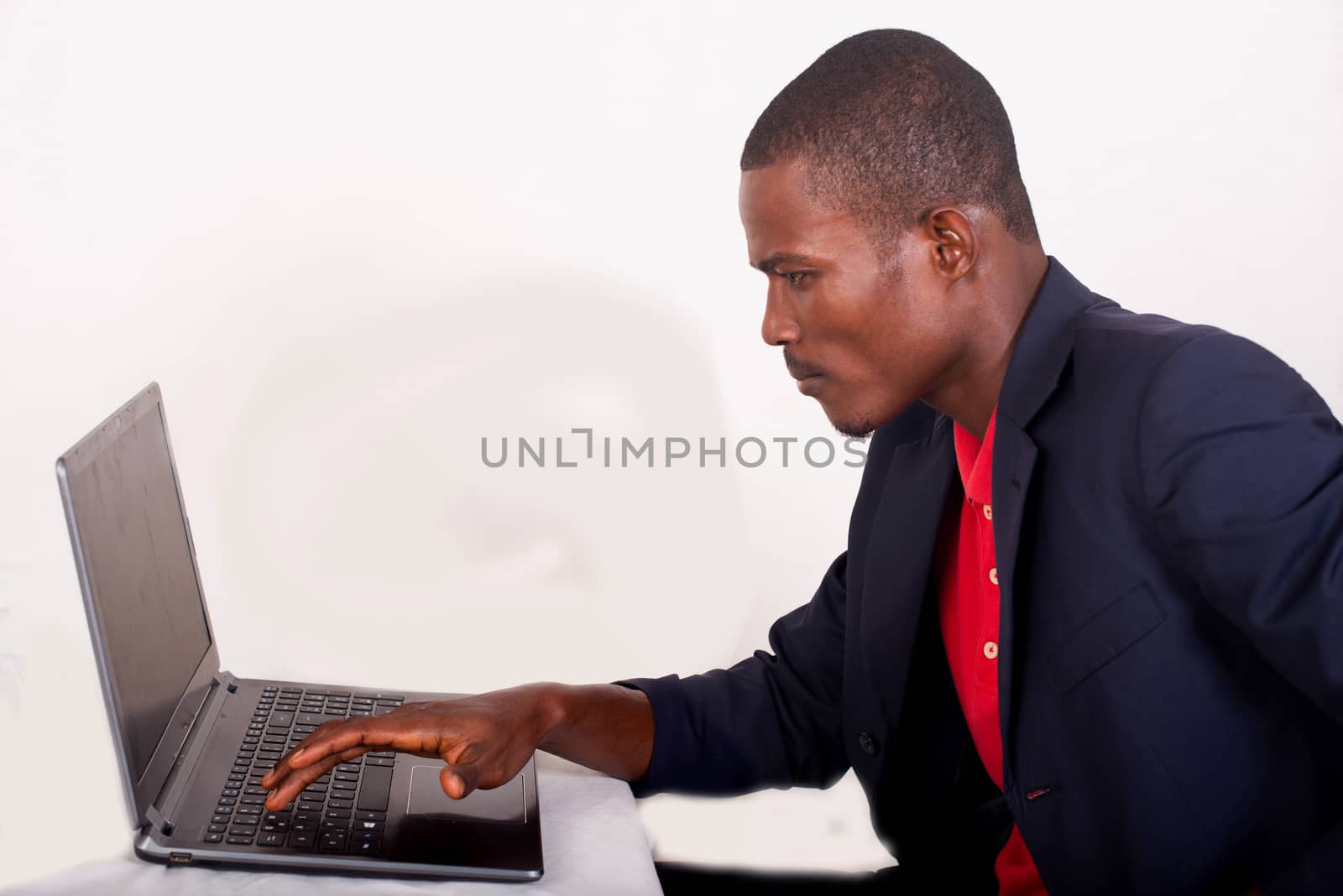 Young businessman working on his laptop in the office. Young african executive sitting at his desk, surfing the internet on laptop.