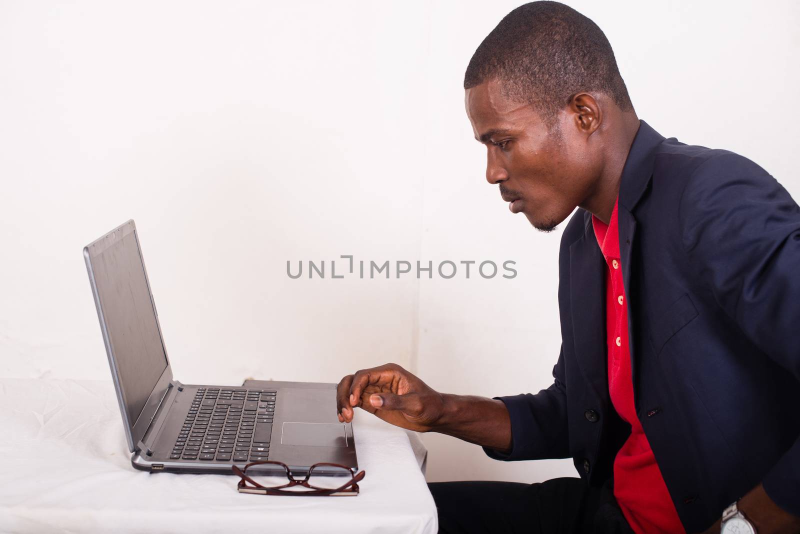 young man in a business suit working at a desk on a laptop