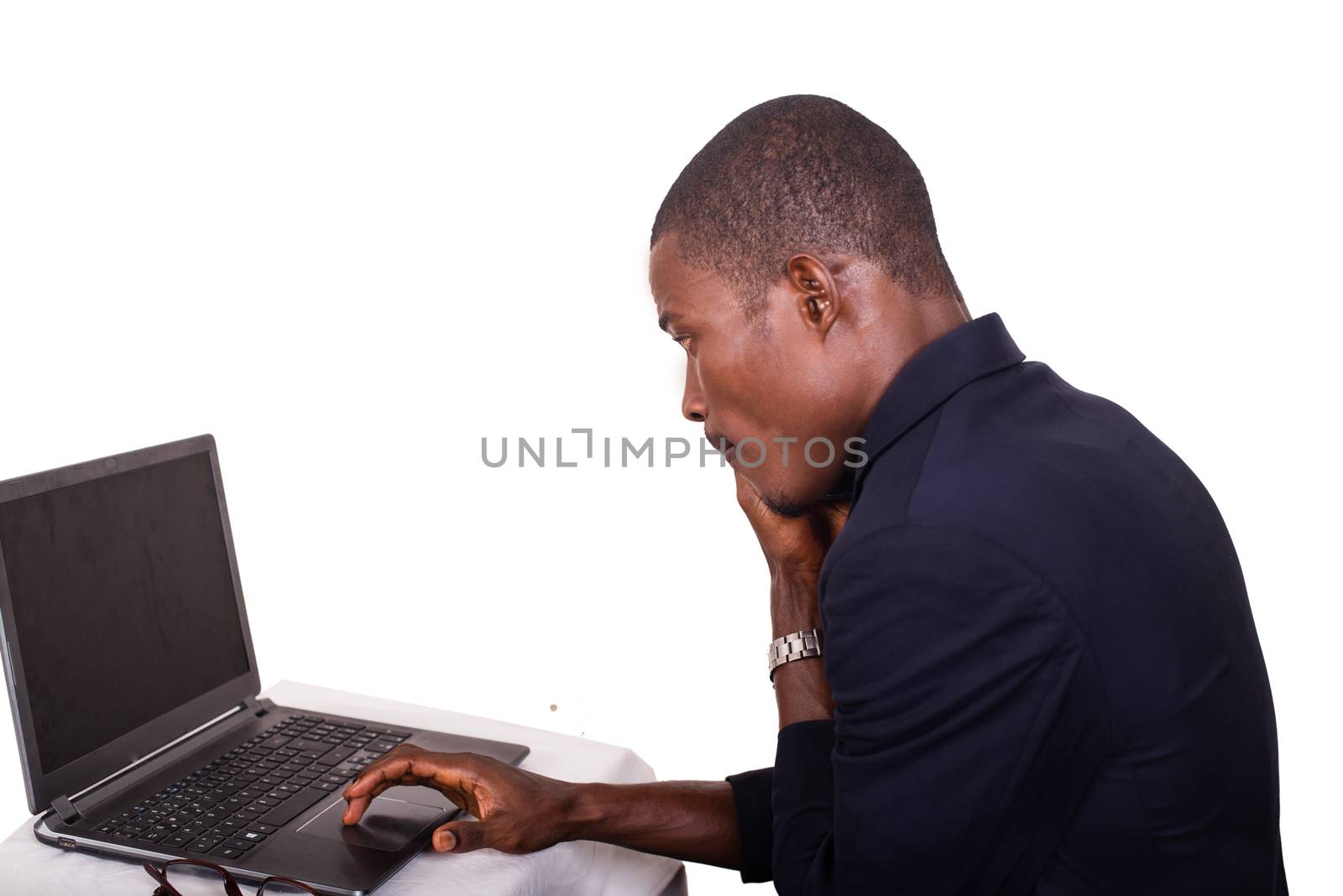 young man in a business suit working at a desk on a laptop