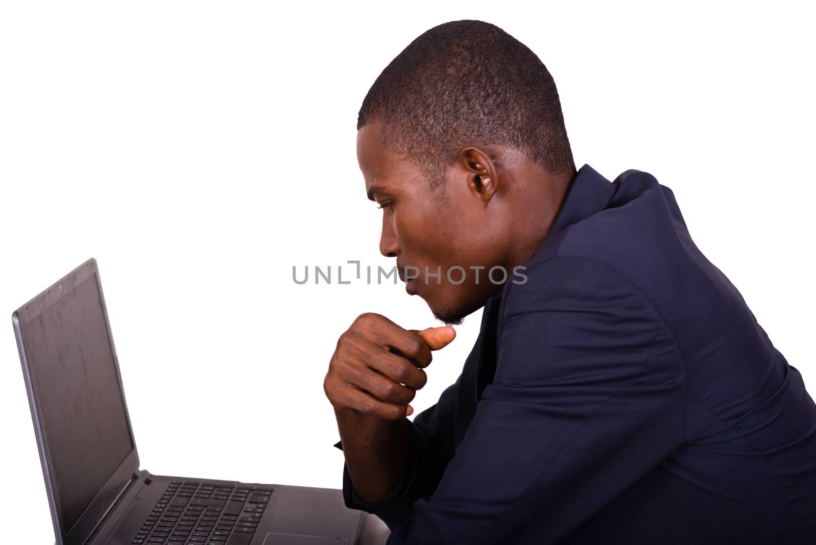 young man in a business suit working at a desk on a laptop