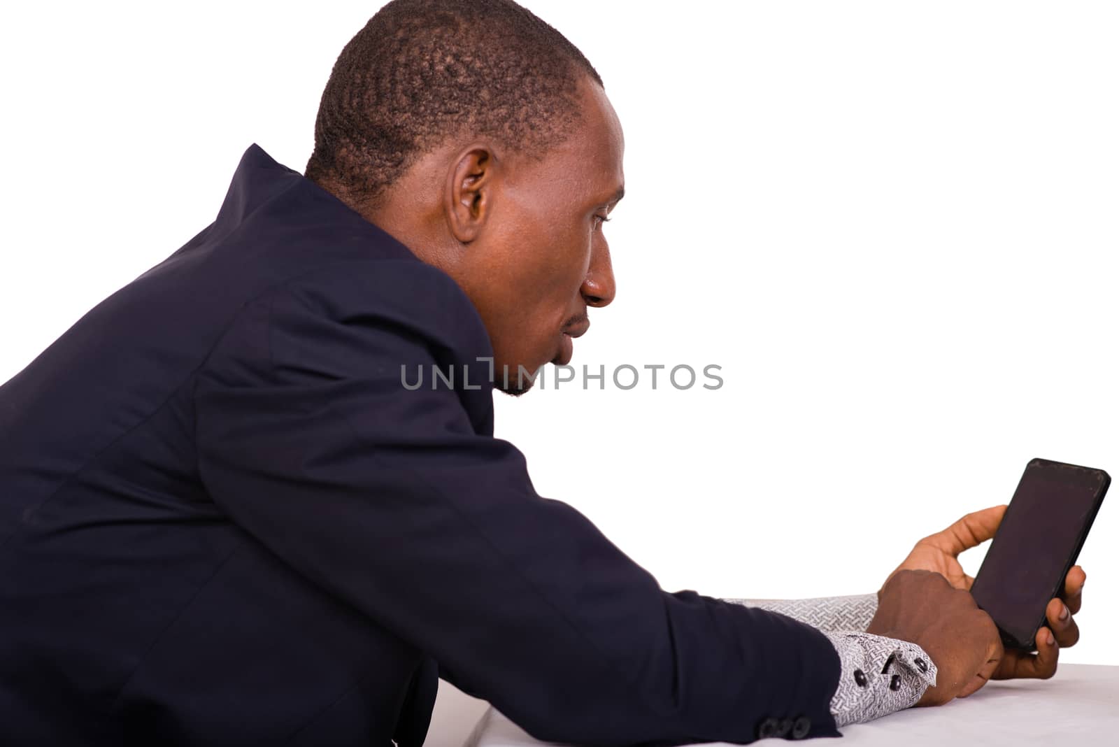 businessman sitting alone looks and consults his cell phone for business