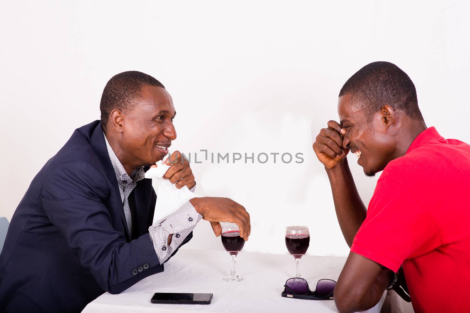 young happy businessmen talking business while drinking wine at table