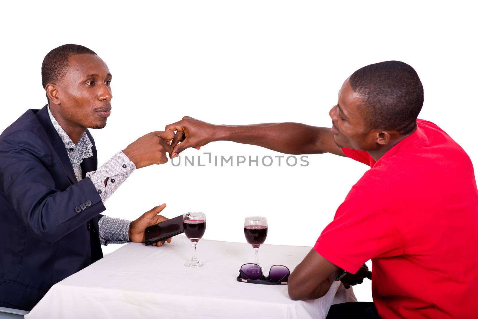 meeting of two happy business people at restaurant sitting in front of glasses of red wine and shaking hands