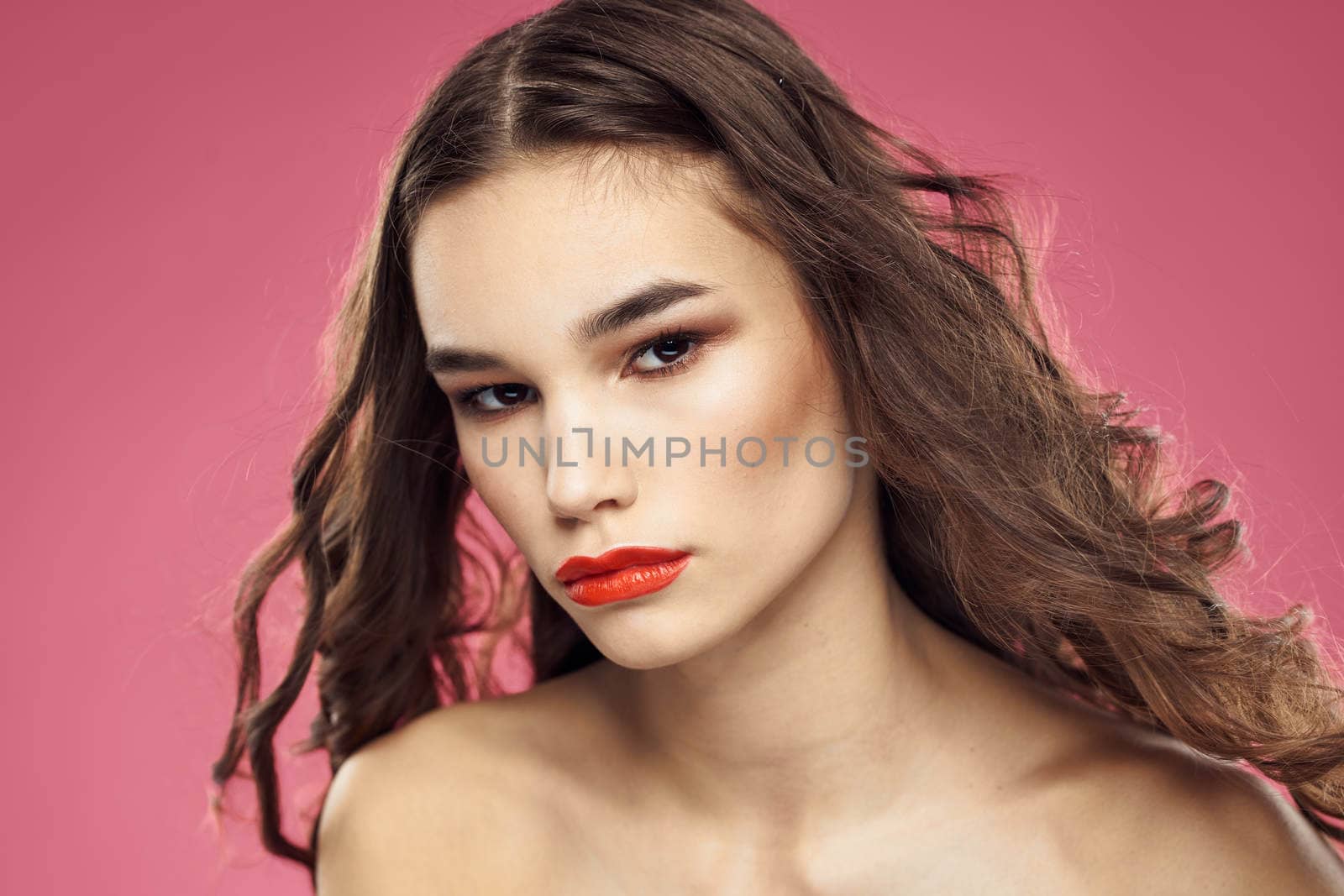 Attractive woman fashionable hairstyle bared shoulders and red lips pink background. High quality photo