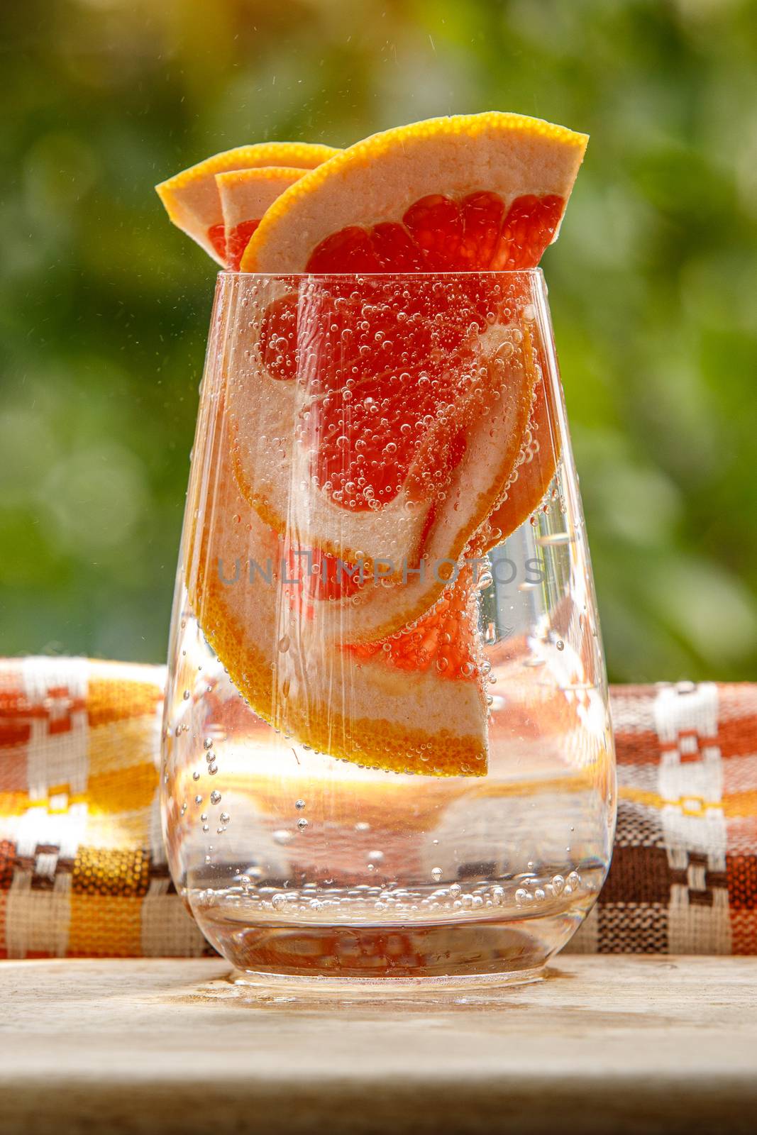 A glass of water with grapefruit in the garden background