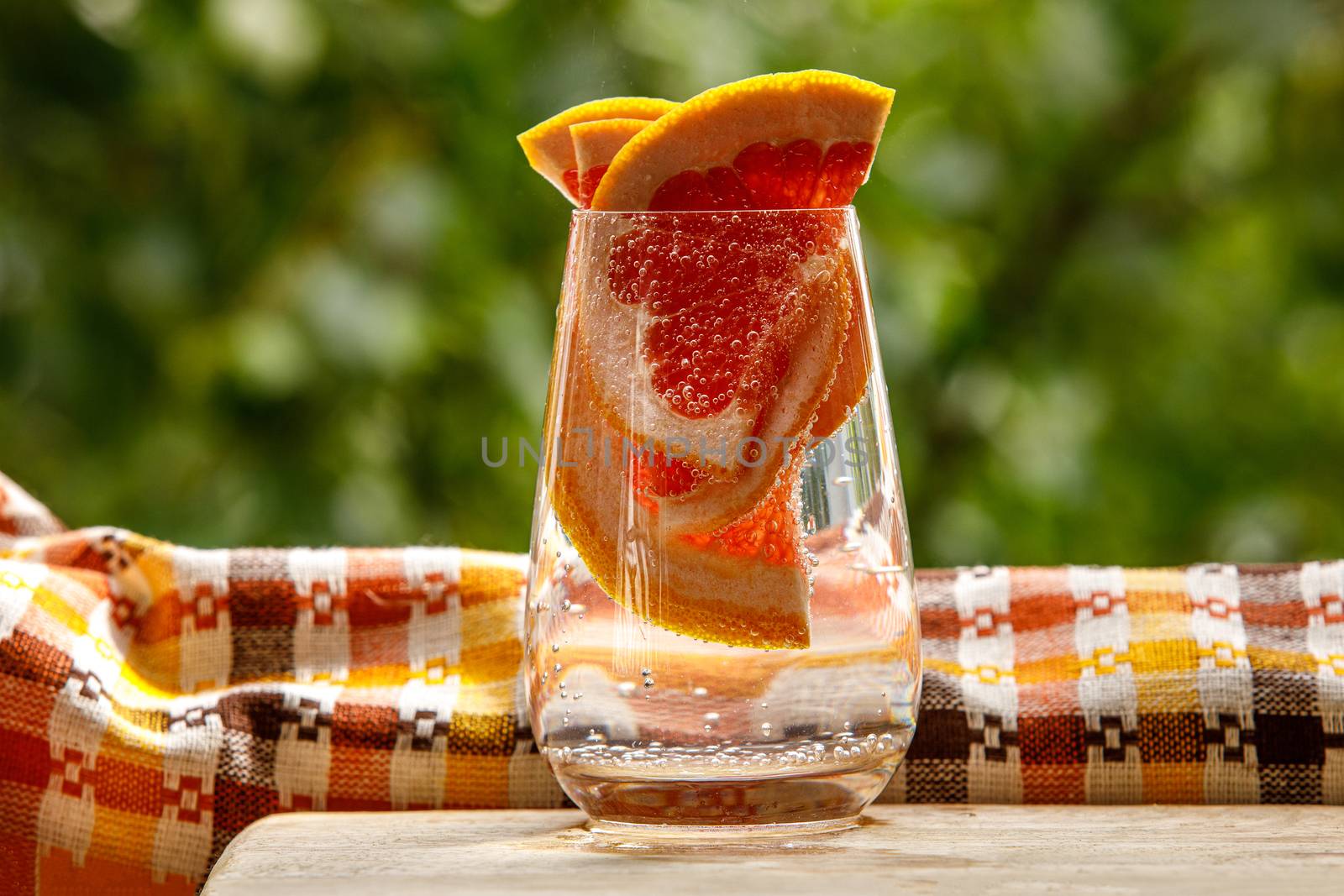 A glass of water with grapefruit in the garden background