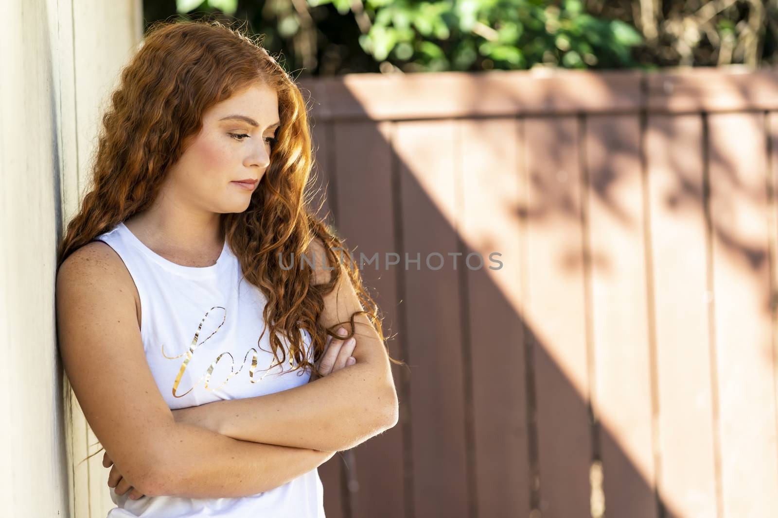 A beautiful redhead model poses outdoors during an autumn day