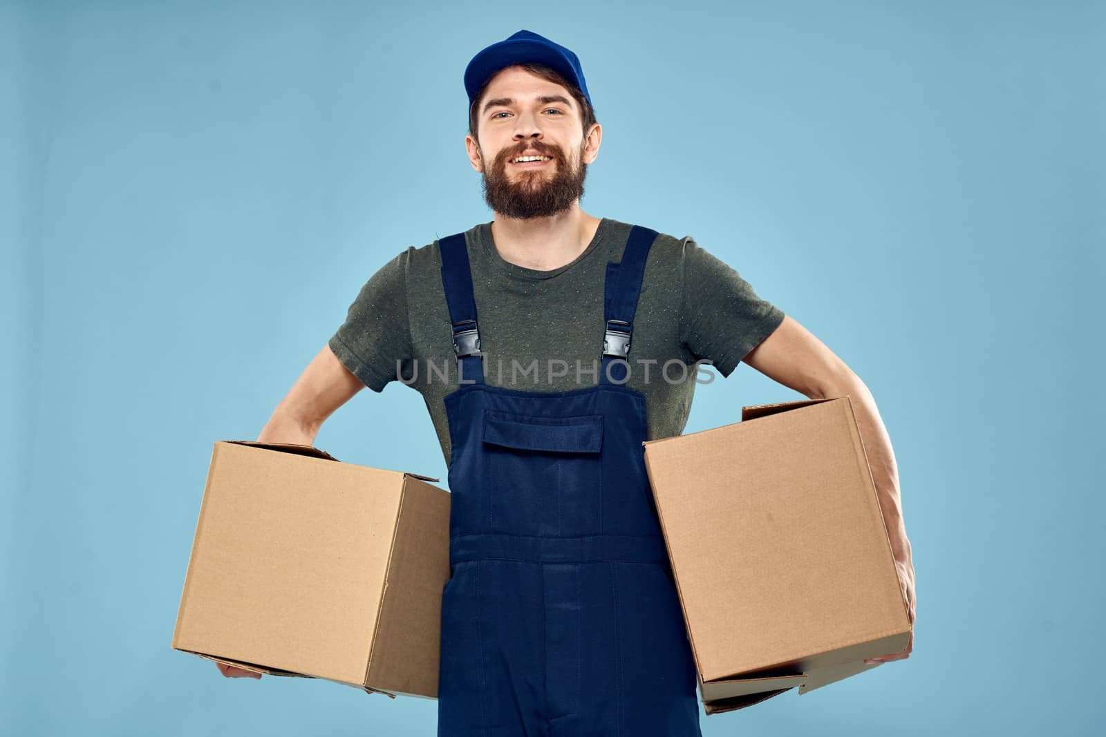 working man boxes in hands delivery service packaging lifestyle blue background. High quality photo