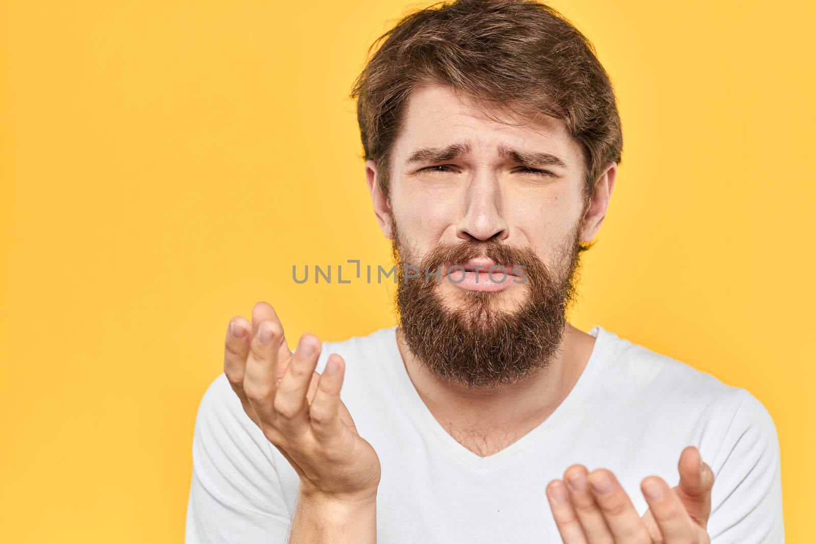 Bearded man emotions gestures with hands facial expression white t-shirt yellow background by SHOTPRIME