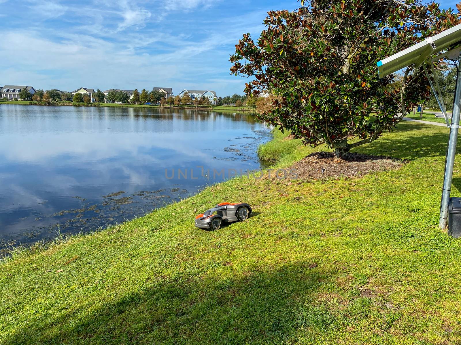 Orlando, FL./USA - 10/16/20:  A Husqvarna autonomous lawn mower mowing near a lake in the Laureate Park neighborhood in Orlando, Florida
