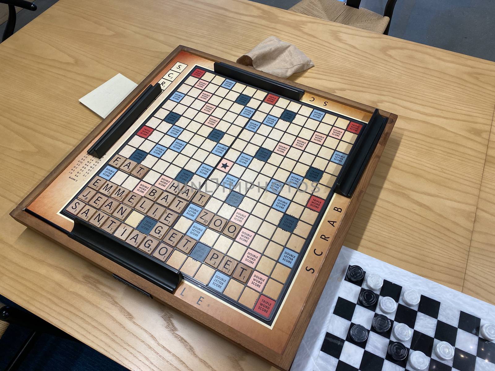 A wooden  Scrabble game board, by Hasbro, on a wooden table by Jshanebutt