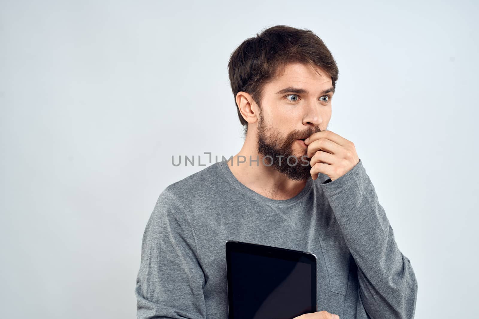 emotional man holding tablet technology communication internet work light background. High quality photo