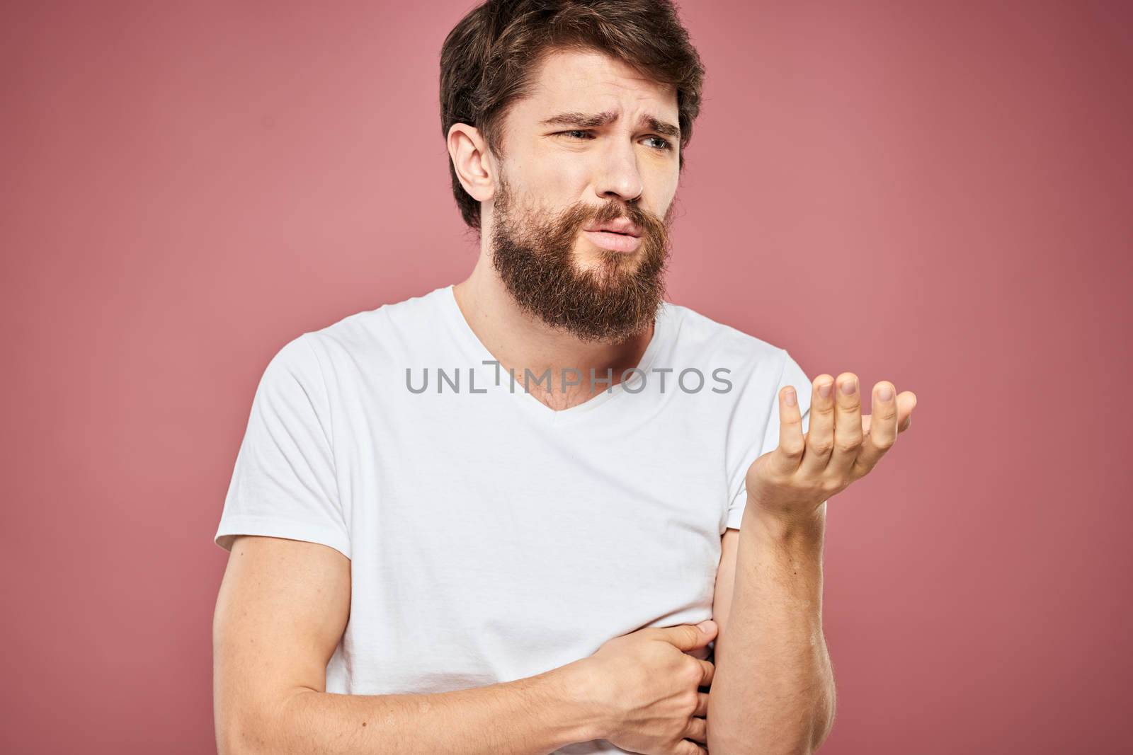 emotional man white t shirt sad facial expression pink background. High quality photo