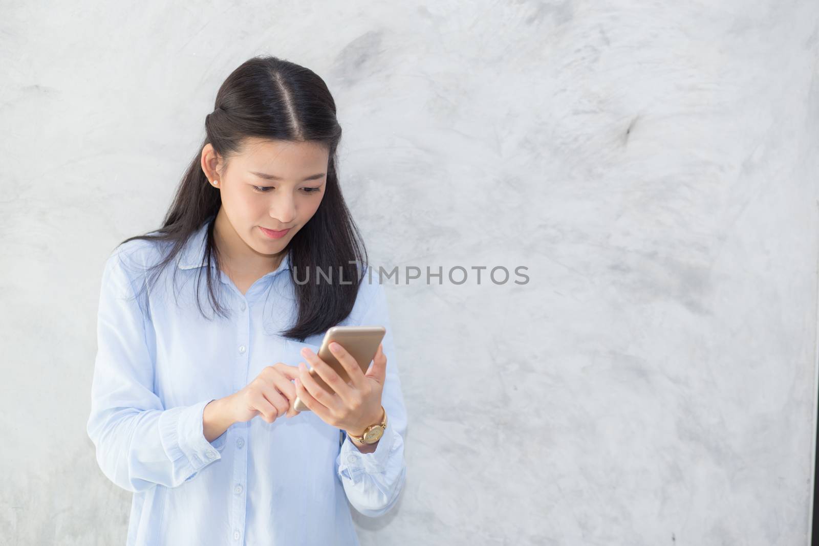 Beautiful young asian woman talking phone and smile standing on cement background, freelancer female calling telephone, communication concept.