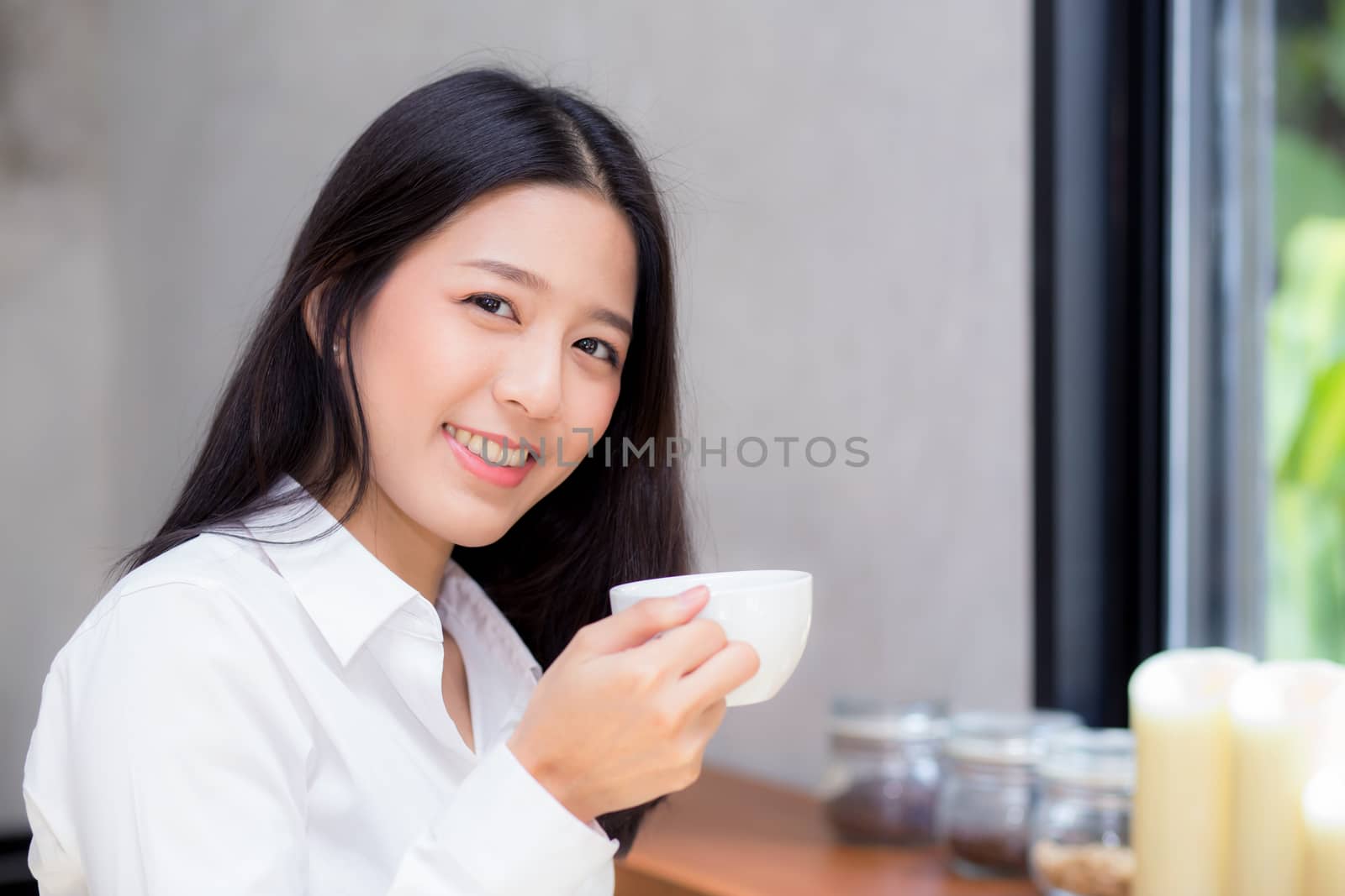 Beautiful  young asian woman drinking coffee and smile in the morning at cafe, girl sitting in coffee shop for breakfast and leisure during free time.