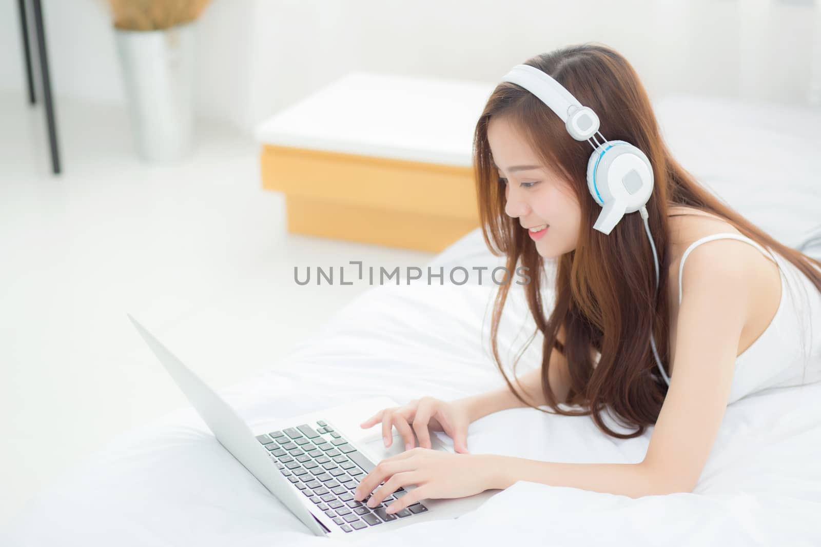 Beautiful asian young woman relax listening to music with headphone and laptop online internet on vacation in bedroom, cheerful of asia girl leisure, lifestyle concept.
