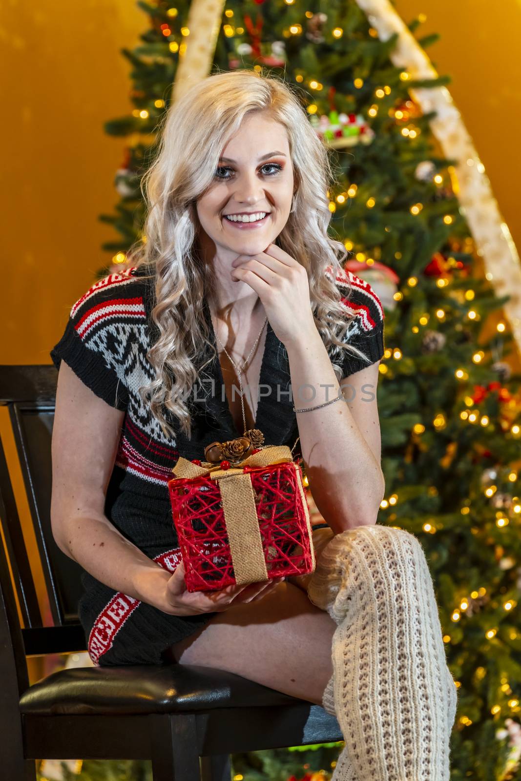 A lovely young Blonde model enjoys the holiday season at home with a Christmas tree and presents by actionsports