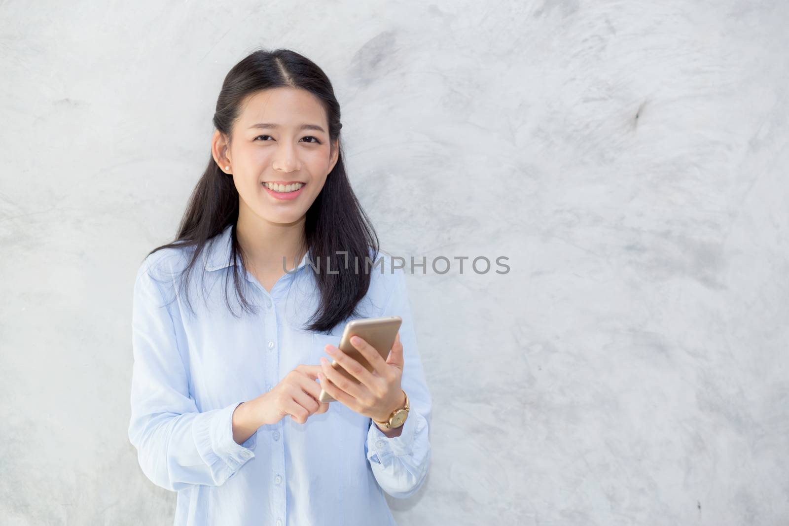 Beautiful young asian woman talking phone and smile standing on cement background, freelancer female calling telephone, communication concept.