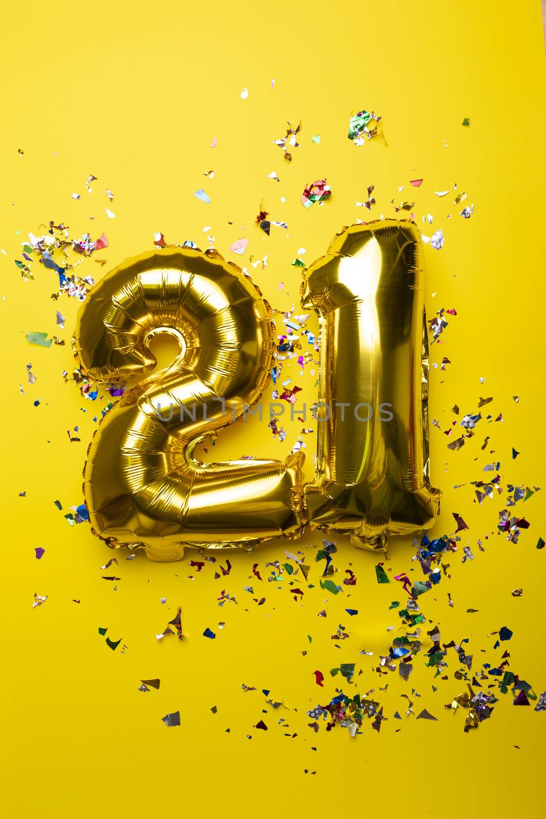 Number 21 from golden foil balloon and confetti on yellow by adamr