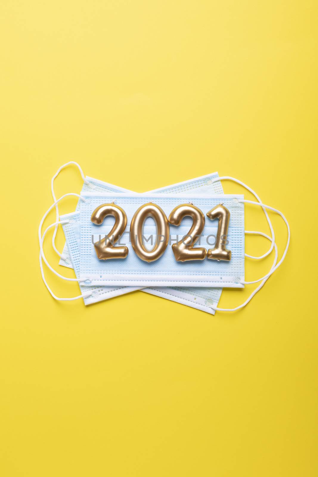 Gold numbers 2021 with face mask on bright yellow background. Happy new pandemic year