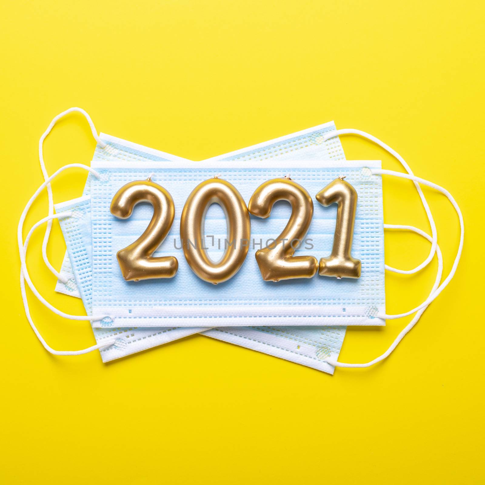 Gold numbers 2021 with face mask on yellow background. Happy new pandemic year