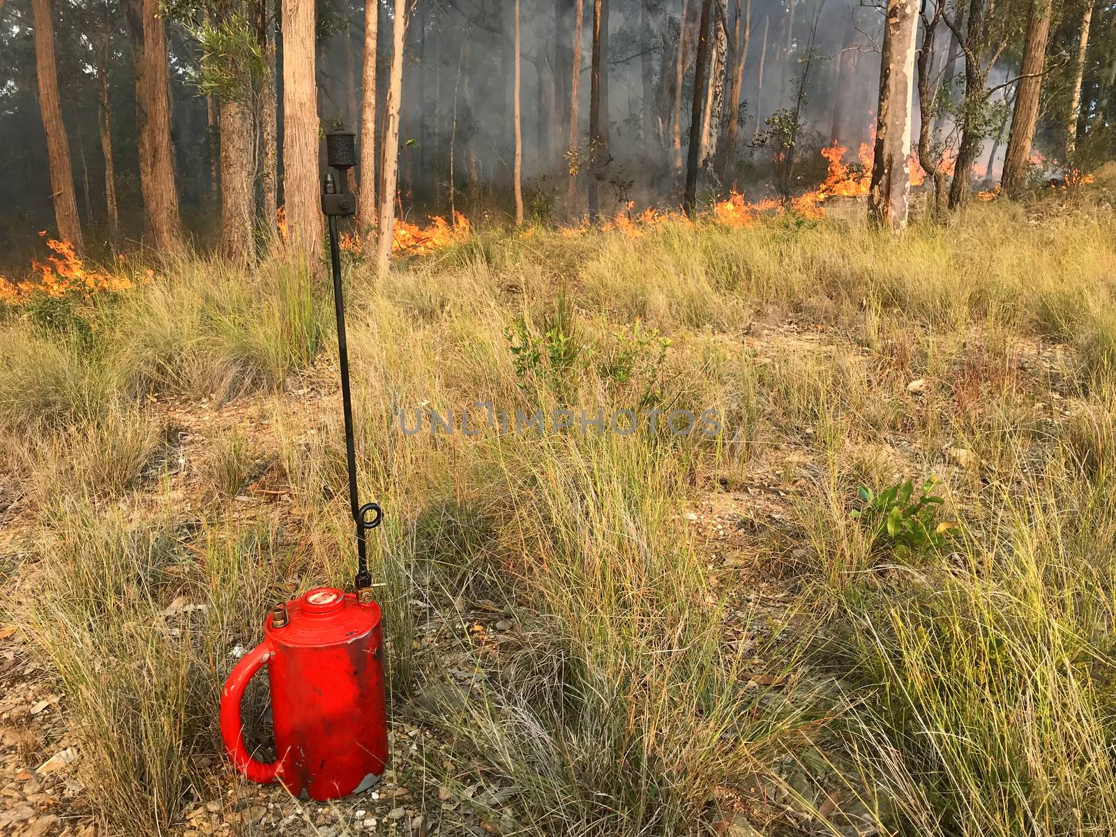 A red drip torch with fire in the background
