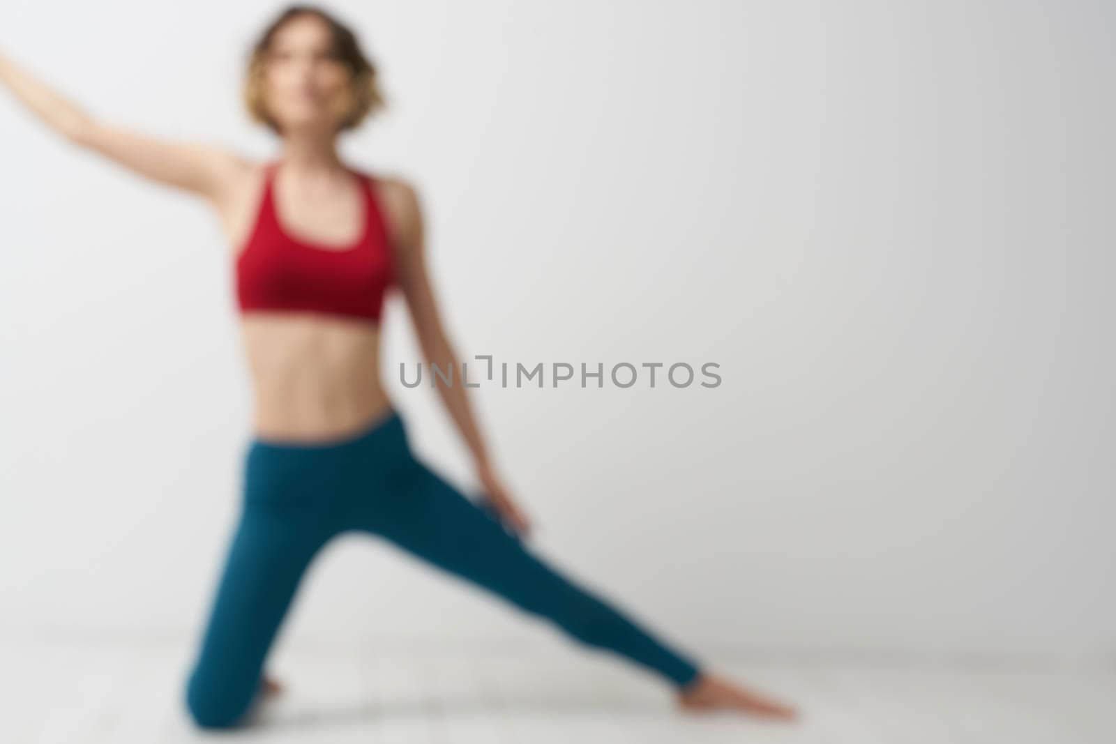 the girl is engaged in yoga on a light background Red T-shirt gesticulating with his hands. High quality photo