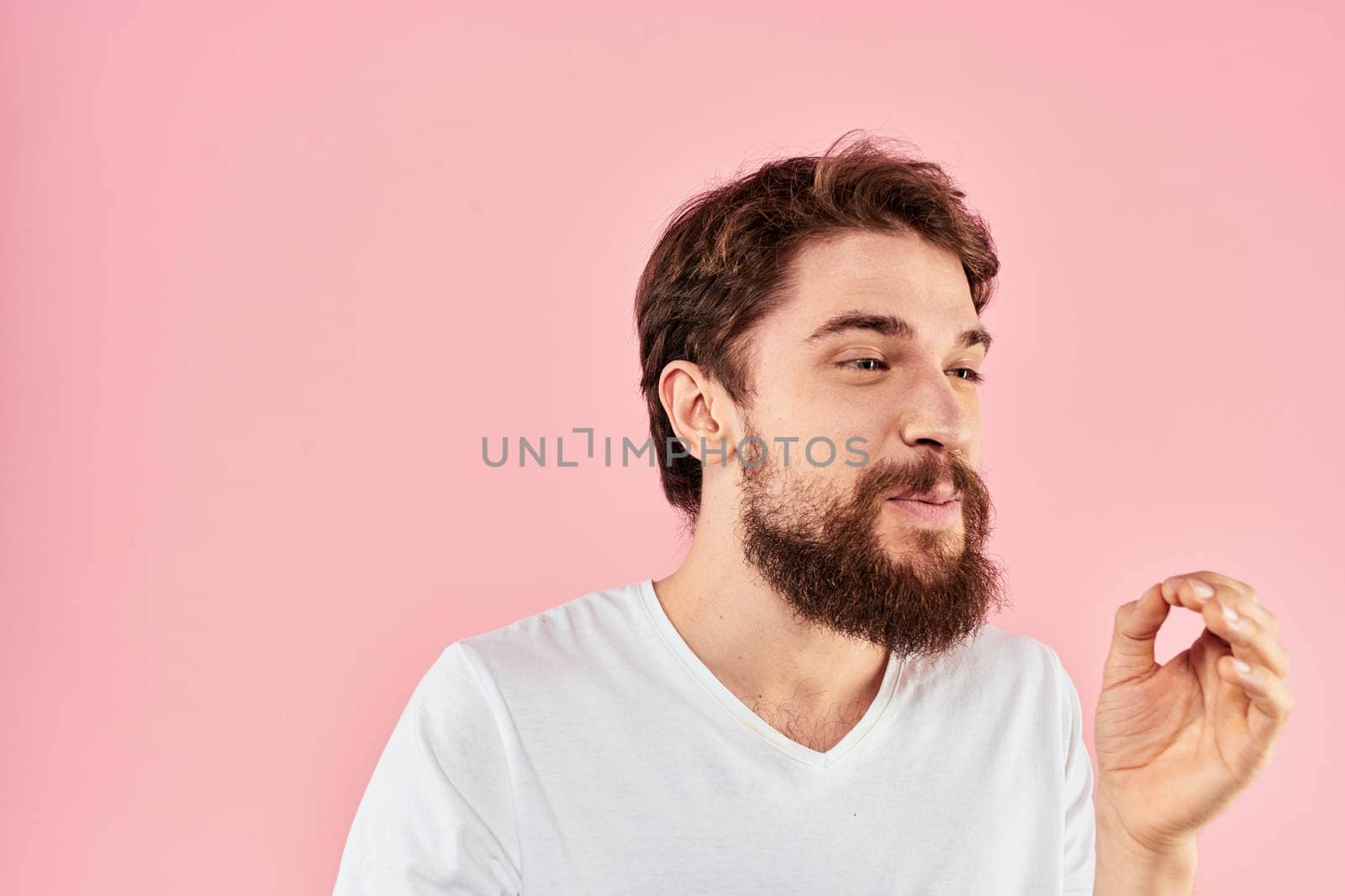 Man in white t-shirt gestures with hands emotions lifestyle cropped view pink background. High quality photo