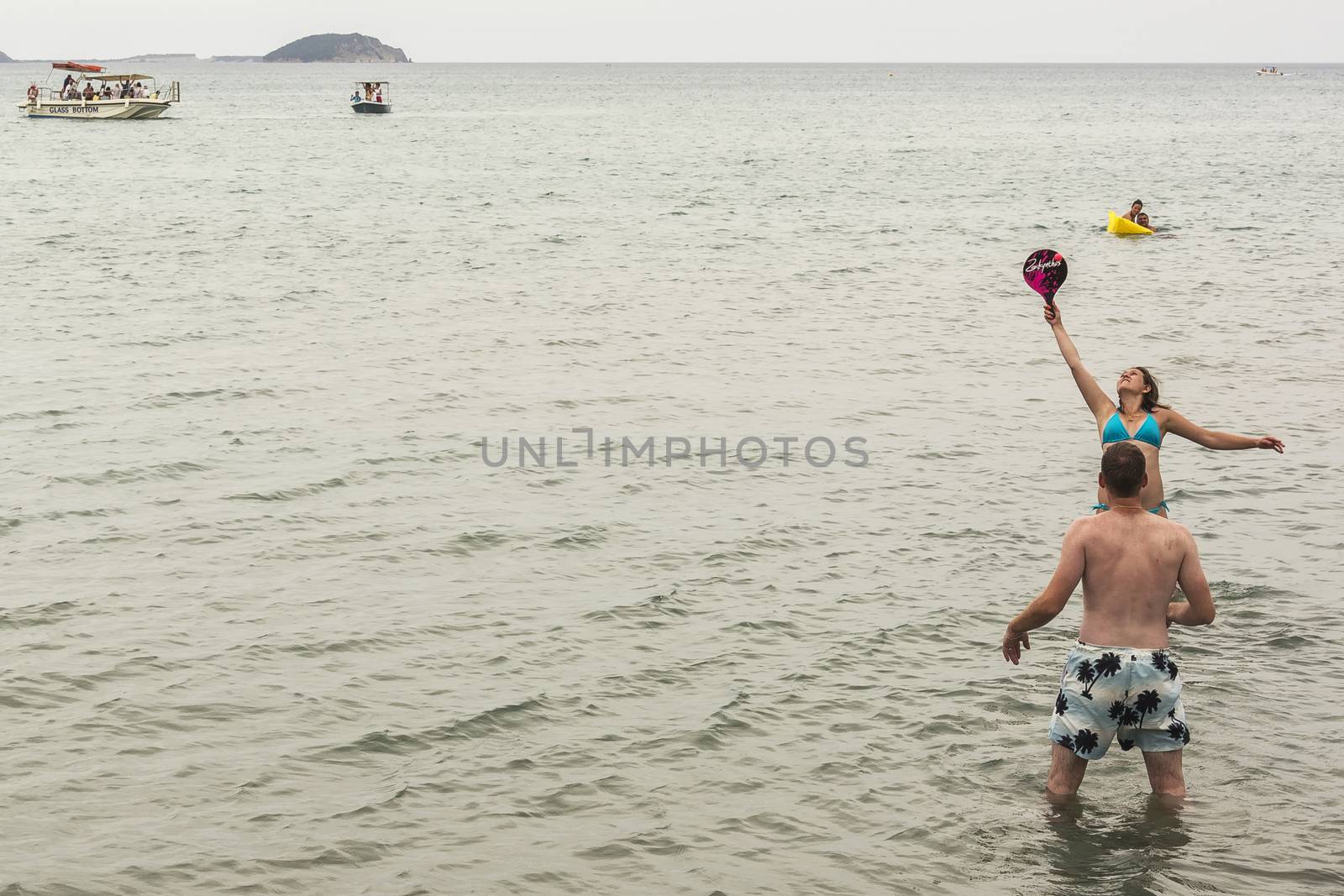 Greece, Zakynthos Island - June 19, 2016: Young woman and young man playing games standing in water