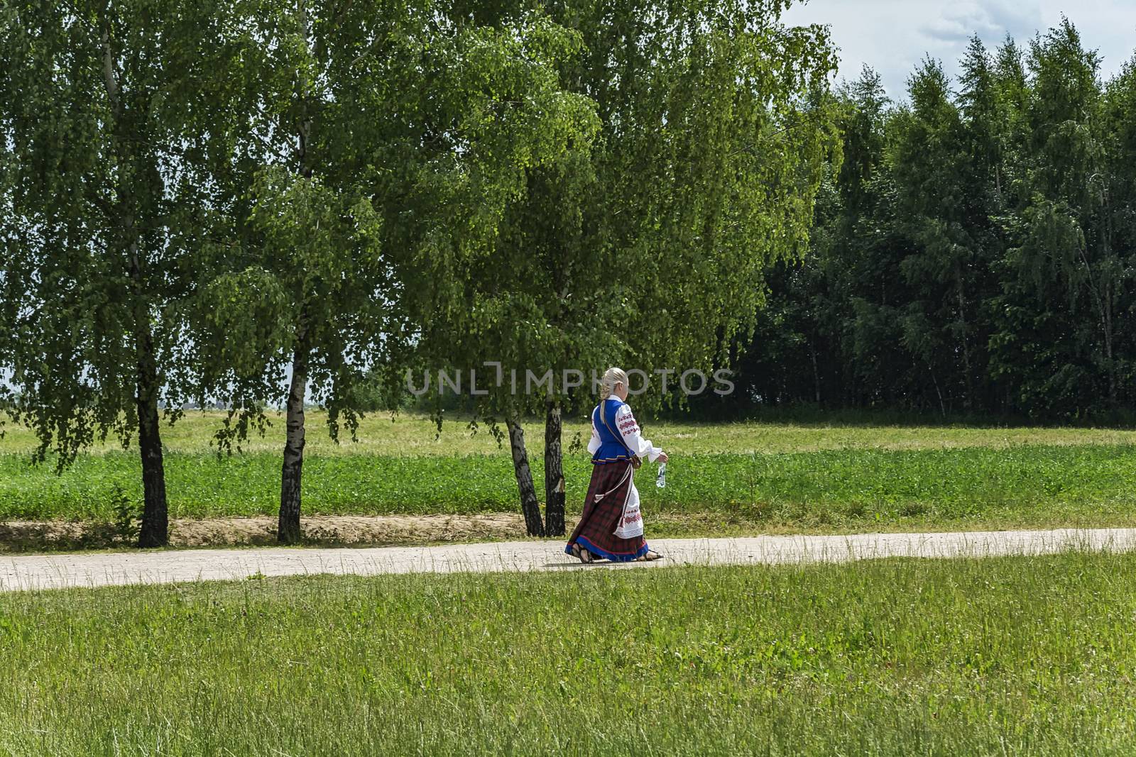 Summer landscape. On a country road is a girl in national clothes