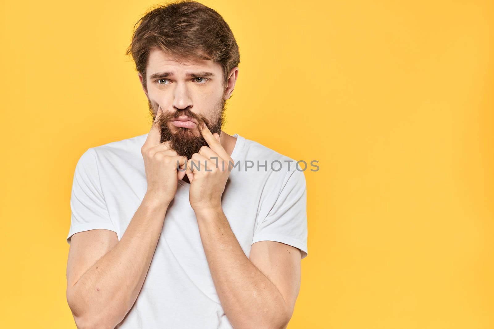 Bearded man emotions gestures with hands facial expression white t-shirt yellow background. High quality photo