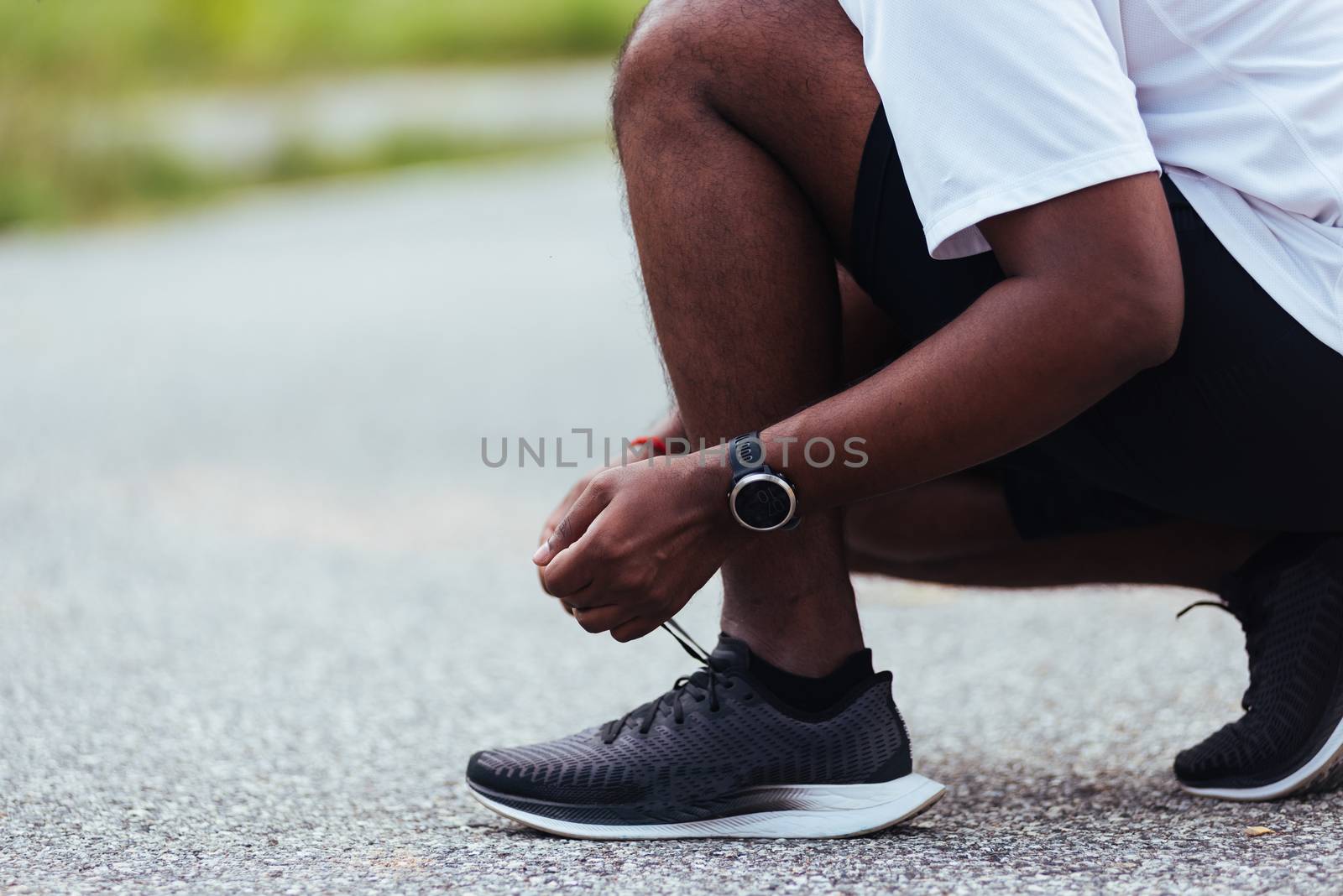 Close up Asian sport runner black man wear watch sitting he trying shoelace running shoes getting ready for jogging and run at the outdoor street health park, healthy exercise workout concept