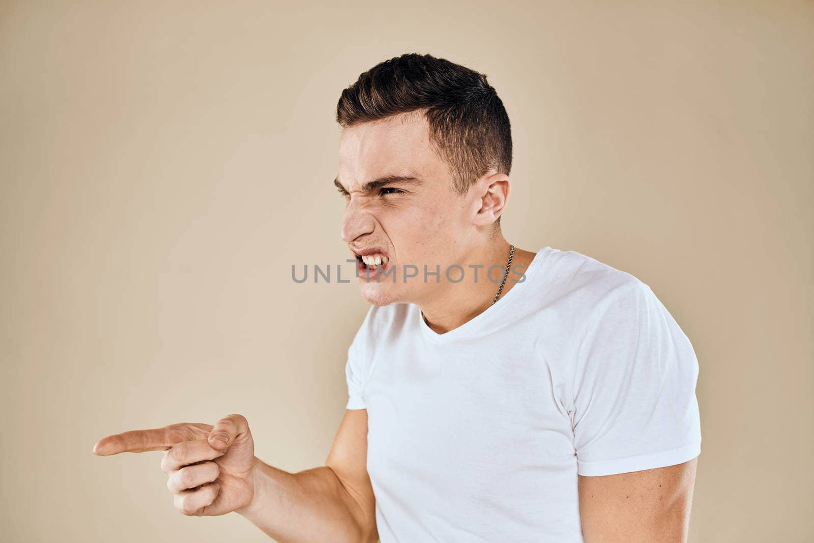 Man with displeased facial expression emotions white t-shirt gestures with hands beige background by SHOTPRIME