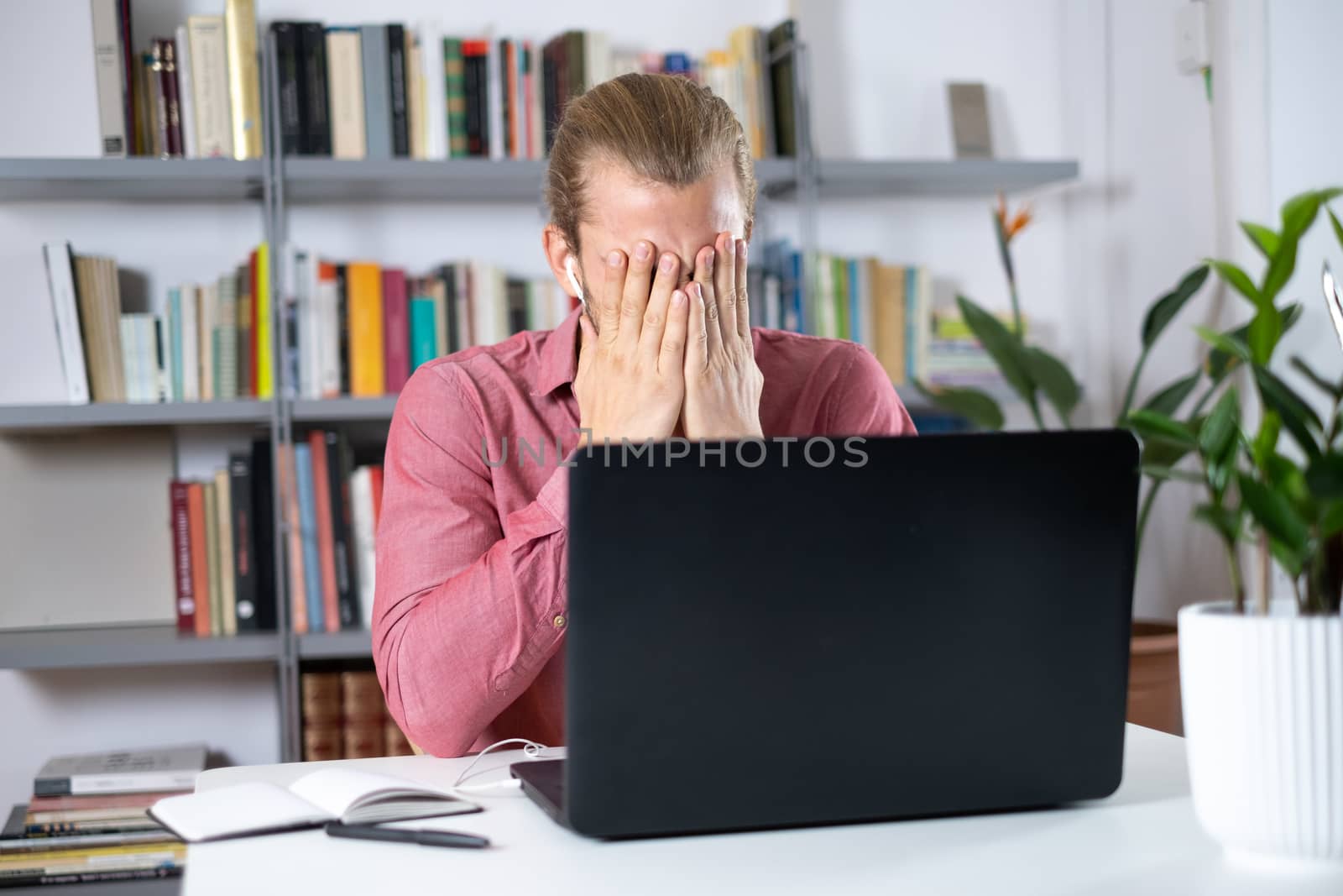 Attractive young man sitting at the table at home working with a laptop feeling worried and frustrated