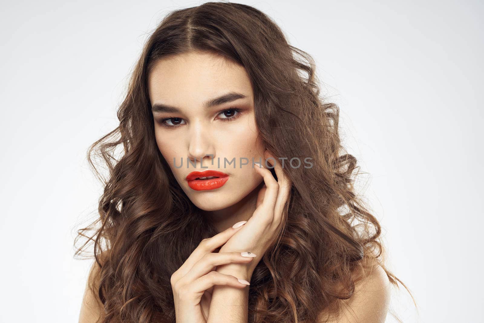 woman with bare shoulders wavy hairstyle glamor makeup light background. High quality photo